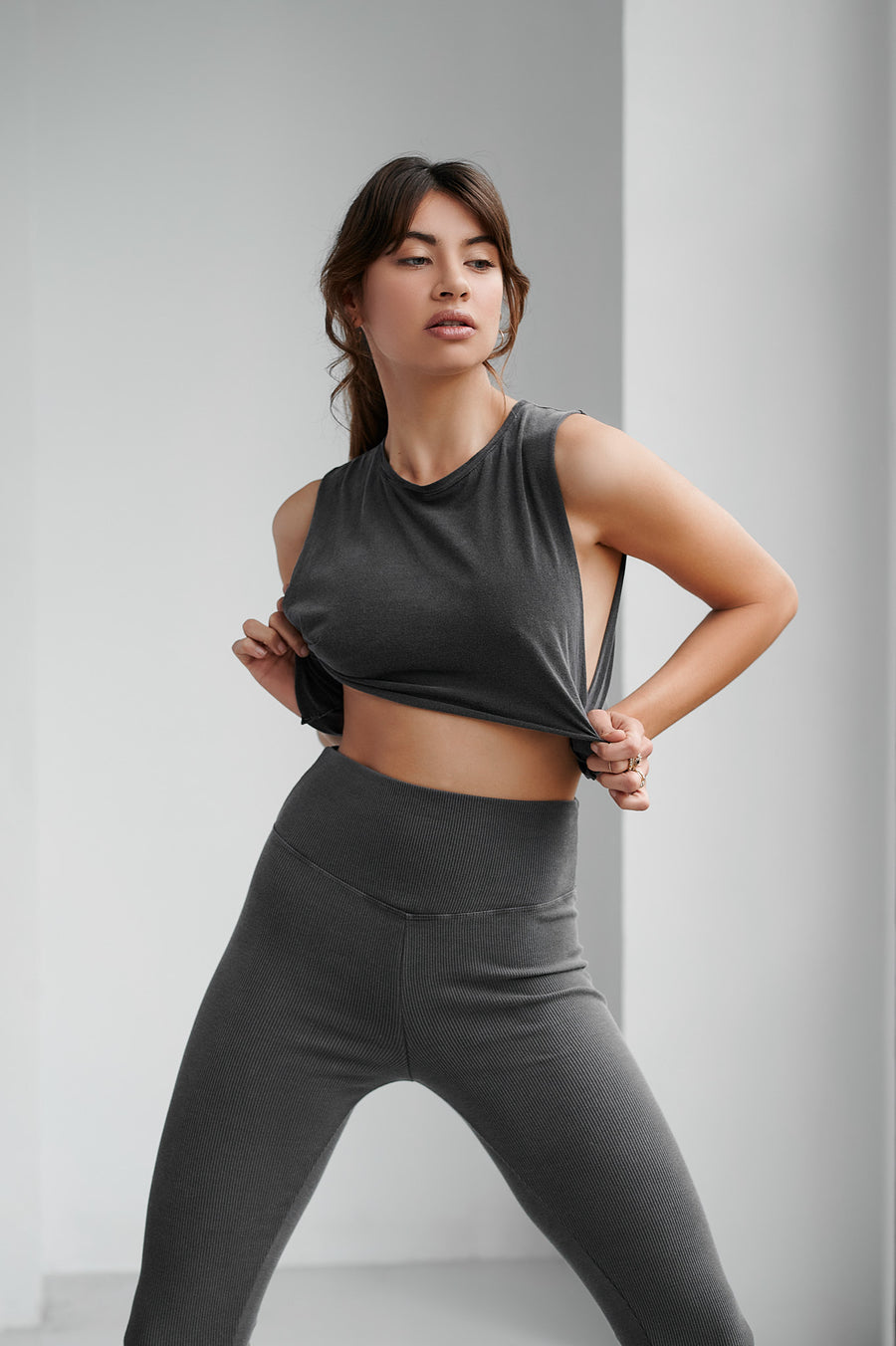 Fika Tank Top - Charcoal Gray -  Front Side - Model Moving freely -High Quality Basic - Streetstyle - Streetwear - Extreme softness - Light touch on the skin, as if you were not wearing anything - Easy-to-Wear & Versatile - Easy-to-Match Style & Color Looks Good - Unique reinterpretation of a basic - deep v-shaped armhole - Loose-fit - Raw Cut finishes - Worn-out feel